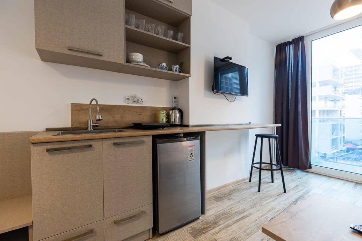 Fully equipped open kitchen seamlessly integrates into the living room, combining functionality with modern aesthetics