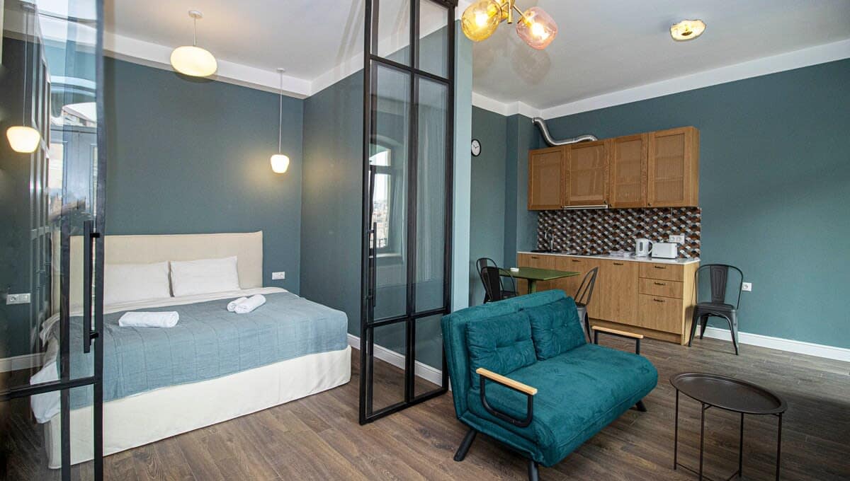 Spacious studio with a cozy bed, modern lighting fixtures, and a stylish seating area.