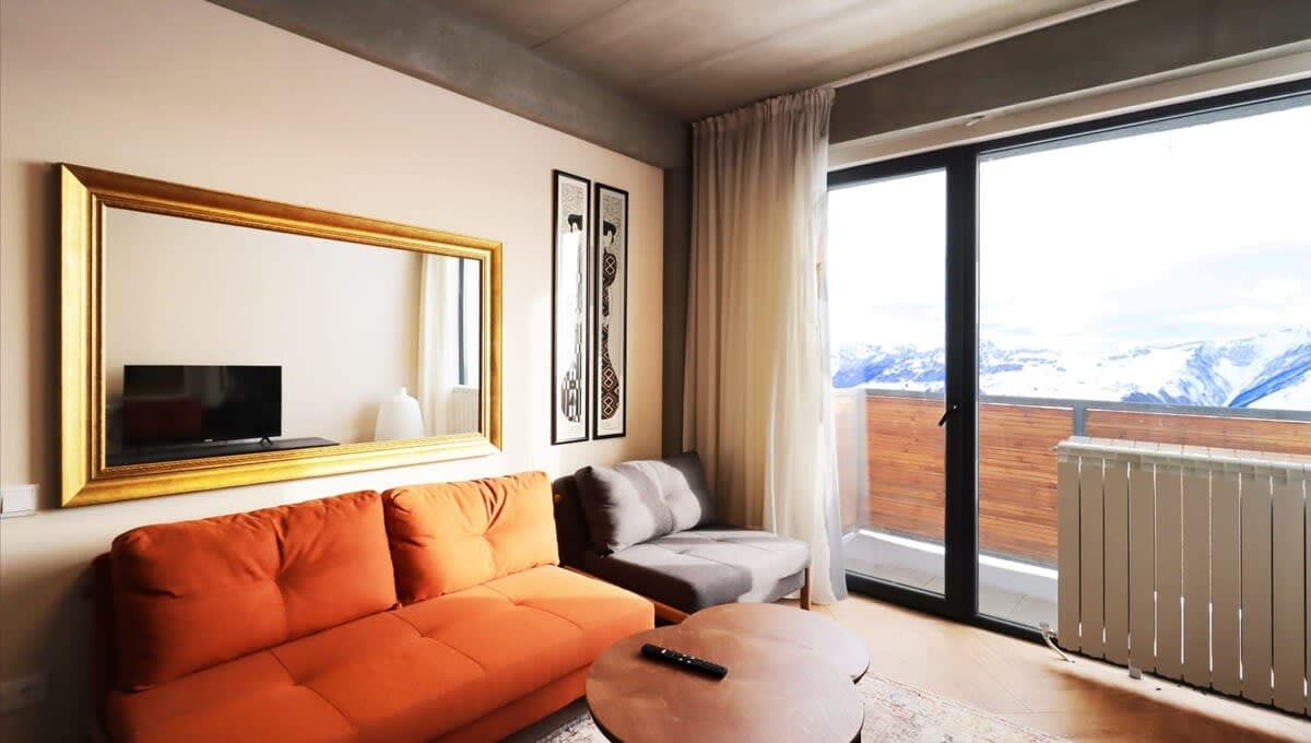 Relax in a cozy living room featuring large windows that provide stunning views of the snowy mountains.