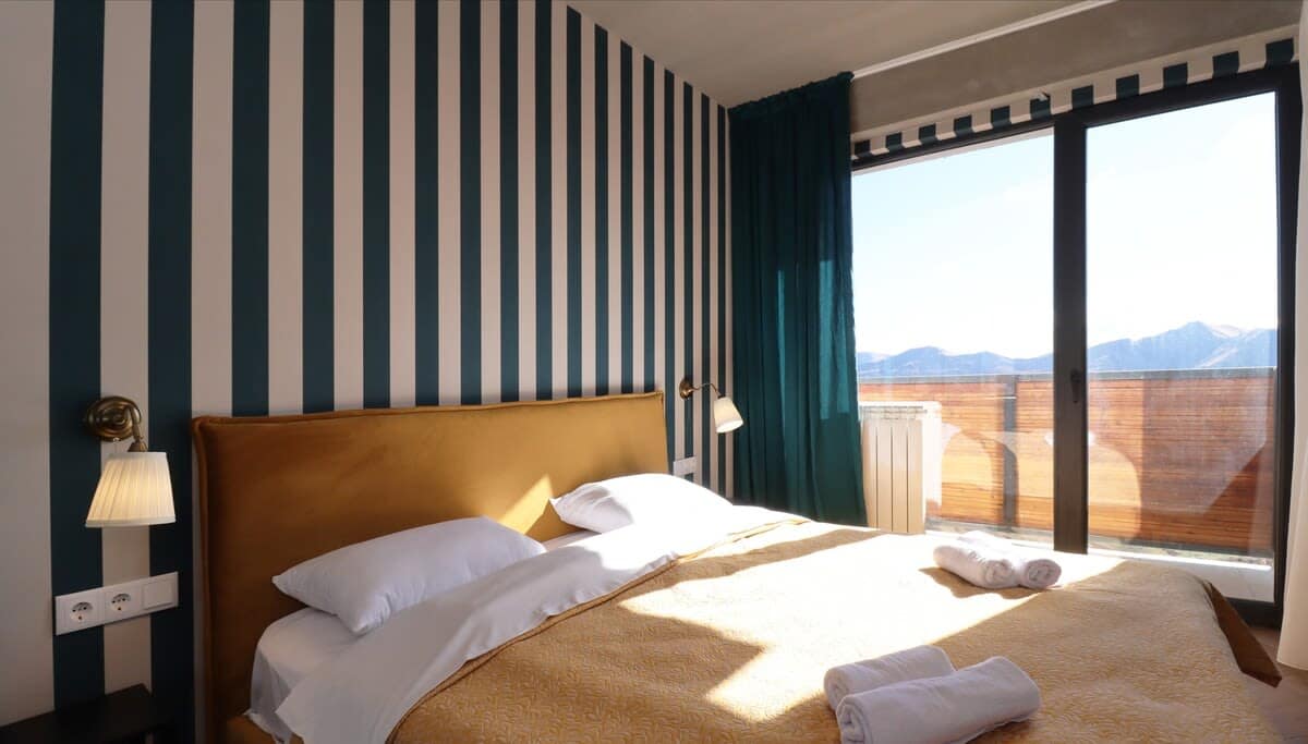 Bedroom featuring green and white stripes, with a king-size bed and fresh linens provided.