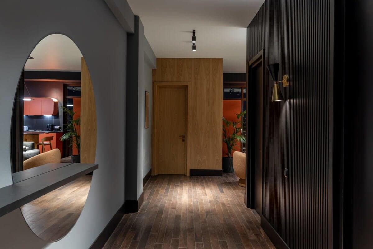 Oval mirrors are paired with black wood panels on the walls, complemented by hardwood floors.