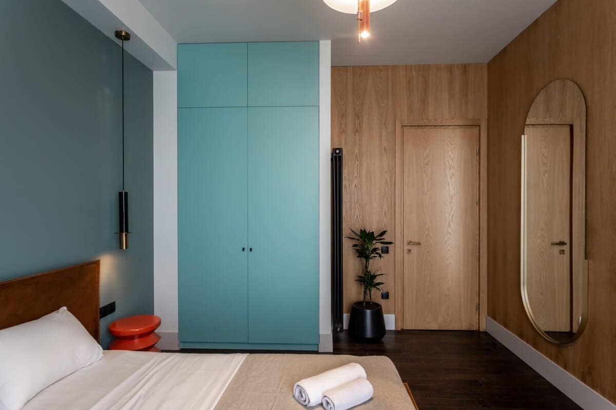 The bedroom features a king-size bed with fresh linens, a long mirror, and a closet.